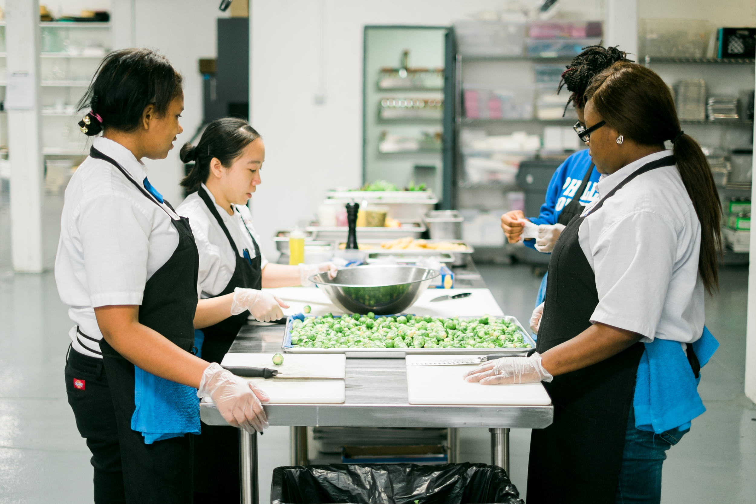 Four students stand in a kitchen, cooking a meal together during an Embarc learning experience